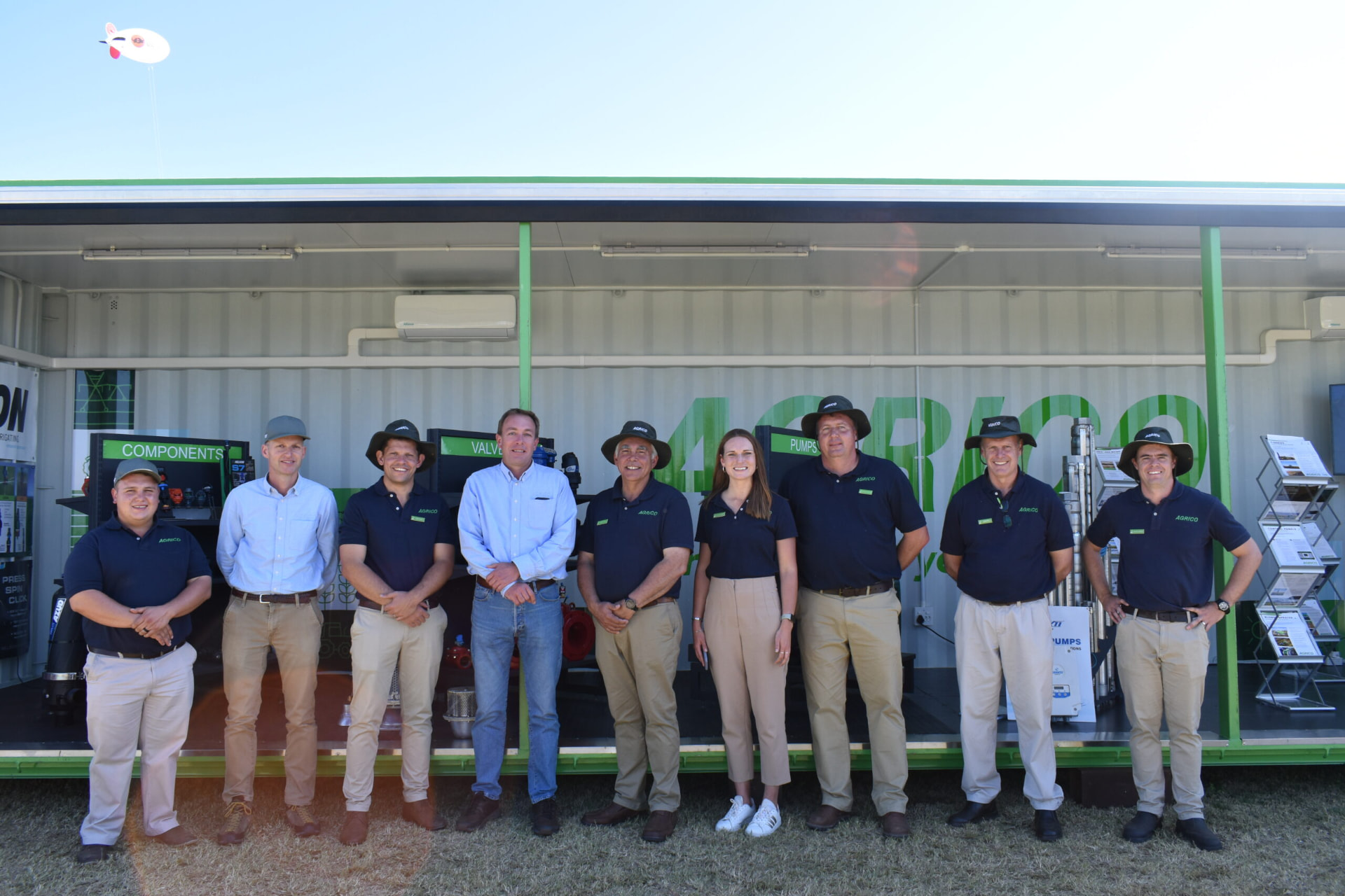 JBS Agrico field and sales team lined up in front of a branded display unit